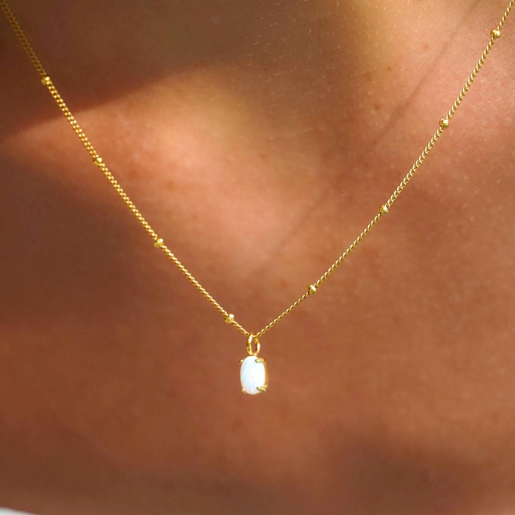 Collar dorado con colgante de ópalo puesto en una modelo