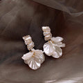 Exquisitos pendientes de pétalos dorados en blanco